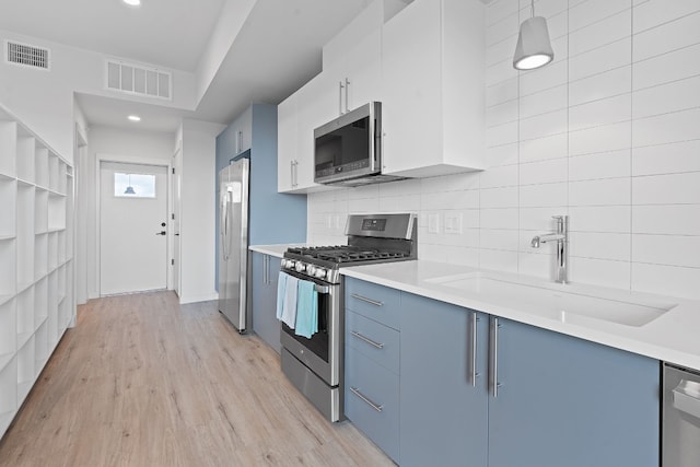 kitchen with stainless steel appliances, light countertops, visible vents, and blue cabinets