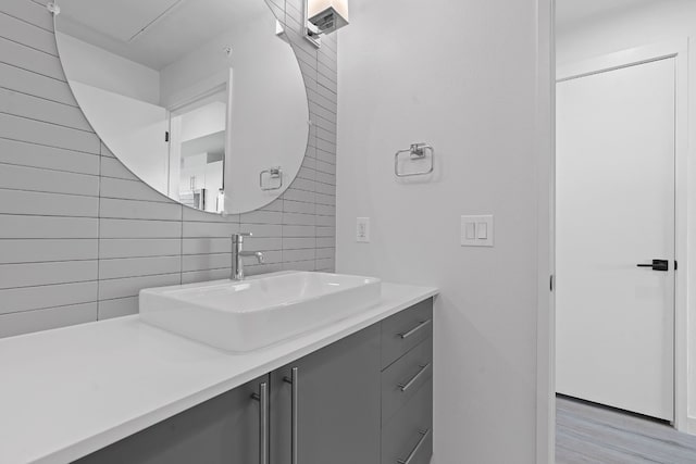 bathroom featuring wood finished floors, backsplash, and vanity