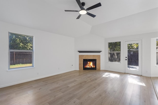 unfurnished living room featuring light wood-type flooring, a tiled fireplace, lofted ceiling, and ceiling fan