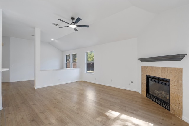 unfurnished living room featuring light wood-type flooring, a tiled fireplace, ceiling fan, and vaulted ceiling