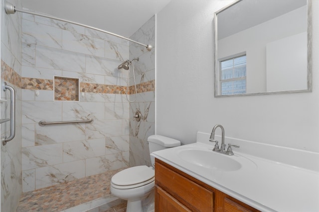 bathroom with toilet, vanity, and tiled shower