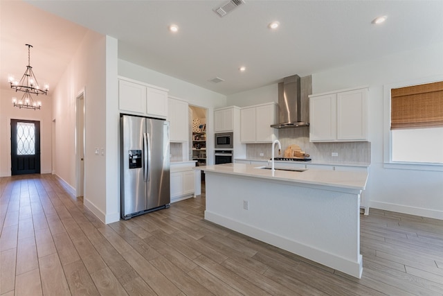 kitchen featuring white cabinetry, wall chimney range hood, a wealth of natural light, and stainless steel appliances