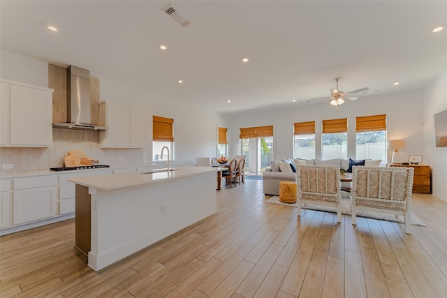 kitchen with white cabinets, wall chimney exhaust hood, and a healthy amount of sunlight