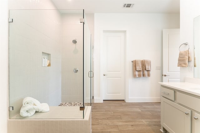 bathroom featuring hardwood / wood-style floors, a shower with door, and vanity