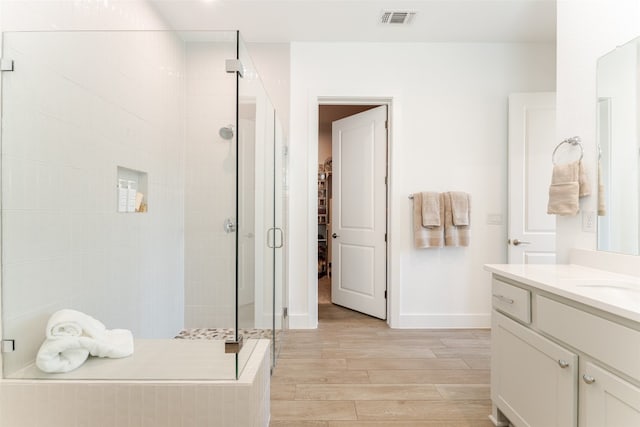 bathroom with walk in shower, wood-type flooring, and vanity