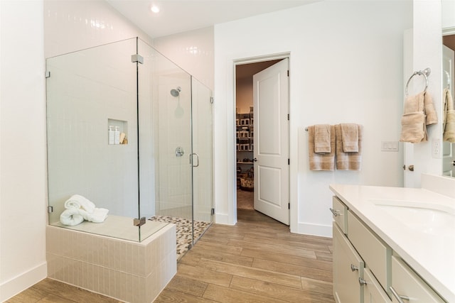 bathroom with walk in shower, wood-type flooring, and vanity