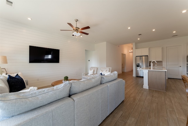 living room featuring sink, ceiling fan, and wood-type flooring