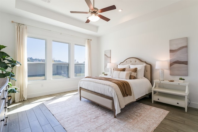 bedroom featuring hardwood / wood-style flooring, ceiling fan, and a raised ceiling