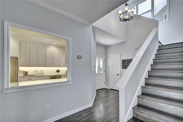 foyer featuring dark hardwood / wood-style floors, crown molding, and a notable chandelier