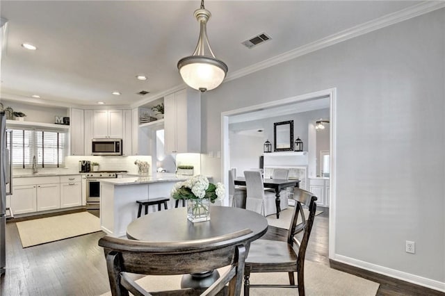 dining area with dark hardwood / wood-style flooring, sink, and ornamental molding