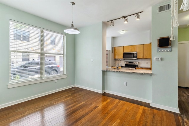 kitchen with stainless steel appliances, dark wood-type flooring, hanging light fixtures, sink, and tasteful backsplash