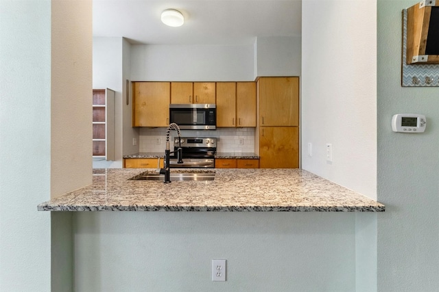 1201 Grove Blvd Unit 1501, Austin, TX 78741 - kitchen with appliances with stainless steel finishes, decorative backsplash, a peninsula, and light stone countertops