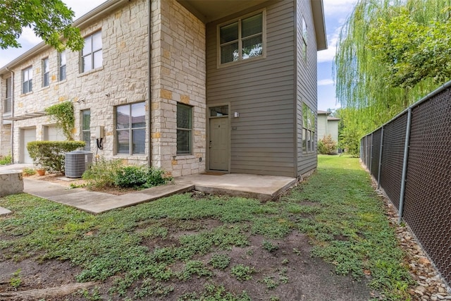 1201 Grove Blvd Unit 1501, Austin, TX 78741 - rear view of house featuring fence, central AC, stone siding, and an attached garage