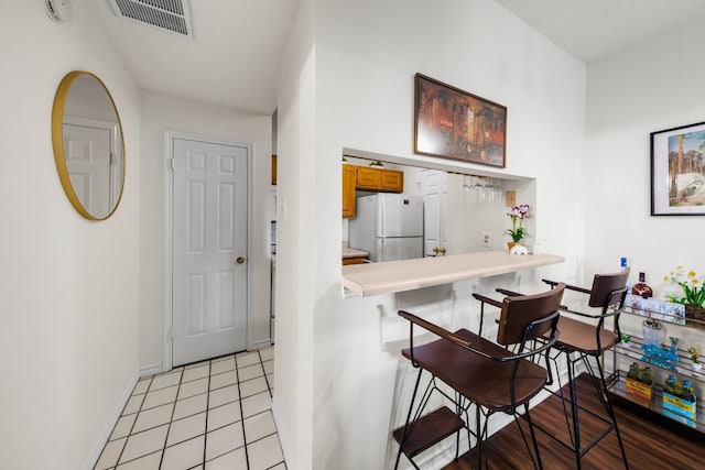 kitchen featuring light tile patterned flooring, white refrigerator, and a breakfast bar