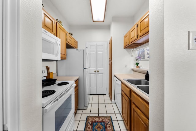 kitchen with light tile patterned floors, white appliances, and sink