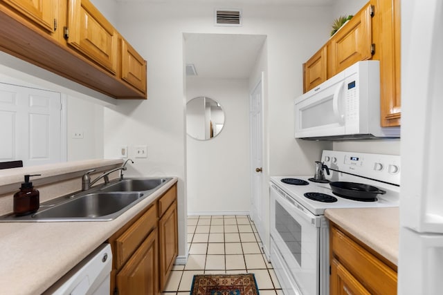 kitchen with light tile patterned floors, white appliances, and sink