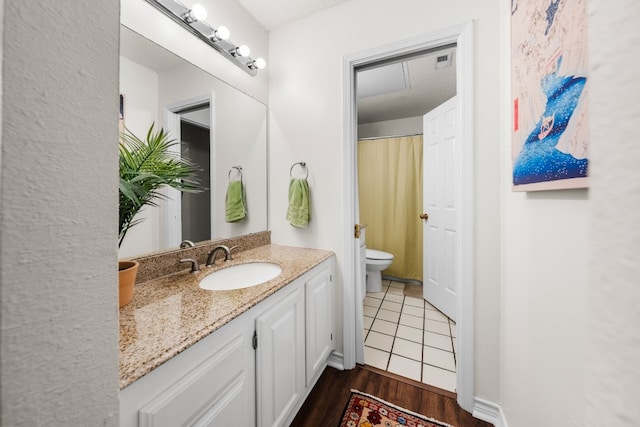 bathroom with toilet, vanity, a textured ceiling, and hardwood / wood-style flooring