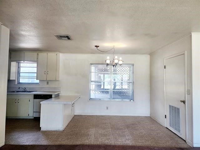 kitchen featuring kitchen peninsula, hanging light fixtures, sink, a notable chandelier, and stainless steel dishwasher