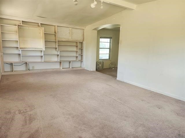 unfurnished living room featuring light colored carpet and beam ceiling