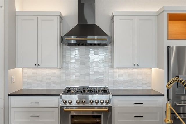 kitchen with appliances with stainless steel finishes, wall chimney exhaust hood, white cabinetry, and backsplash