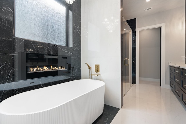 bathroom with tile patterned flooring, a premium fireplace, independent shower and bath, vanity, and tile walls