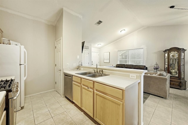 kitchen with sink, light tile patterned floors, appliances with stainless steel finishes, light brown cabinetry, and vaulted ceiling