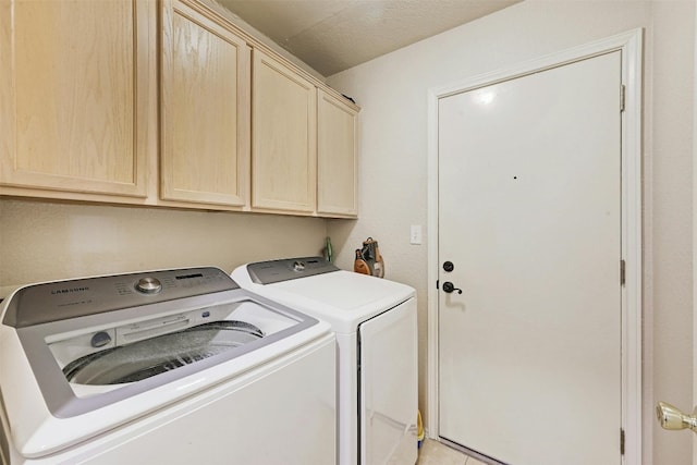 washroom with cabinets, light tile patterned floors, and washing machine and clothes dryer