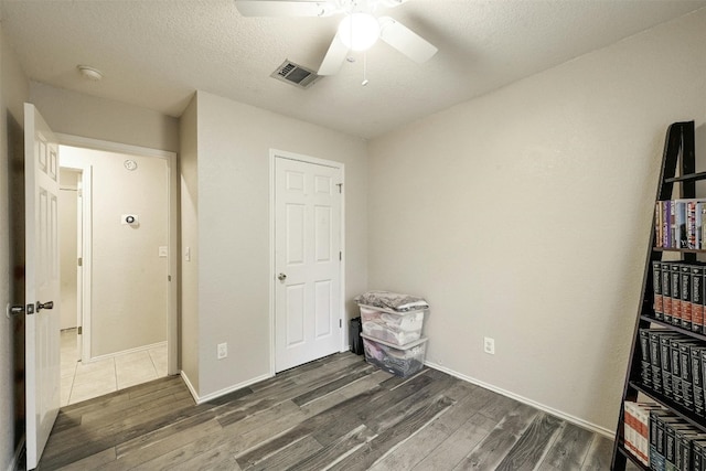 bedroom with dark wood-type flooring, a textured ceiling, and ceiling fan