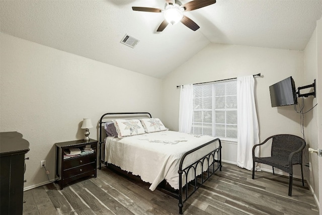 bedroom featuring lofted ceiling, a textured ceiling, dark wood-type flooring, and ceiling fan