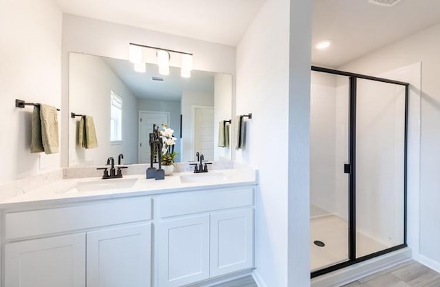 bathroom featuring vanity, a shower with shower door, and wood-type flooring