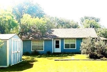 back of house with a lawn and a storage shed