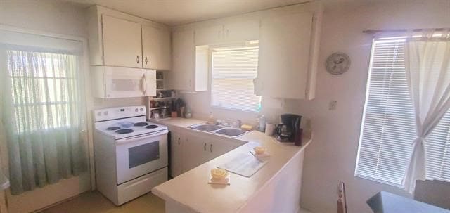 kitchen featuring a wealth of natural light, white appliances, sink, and white cabinets