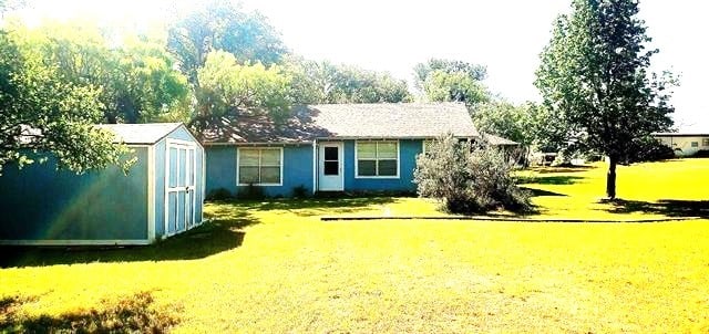 view of front of home featuring a storage unit and a front yard