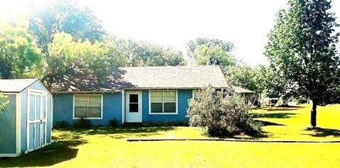 back of house with a lawn and a storage shed