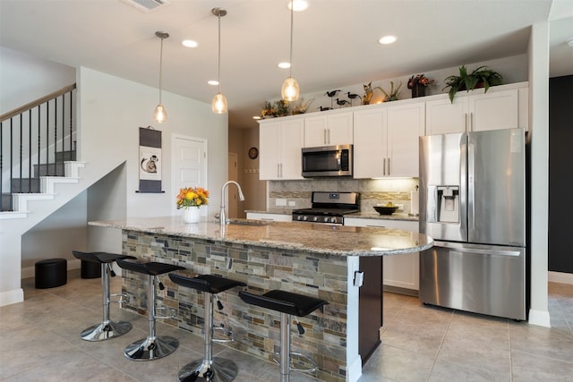 kitchen featuring white cabinetry, pendant lighting, an island with sink, and stainless steel appliances