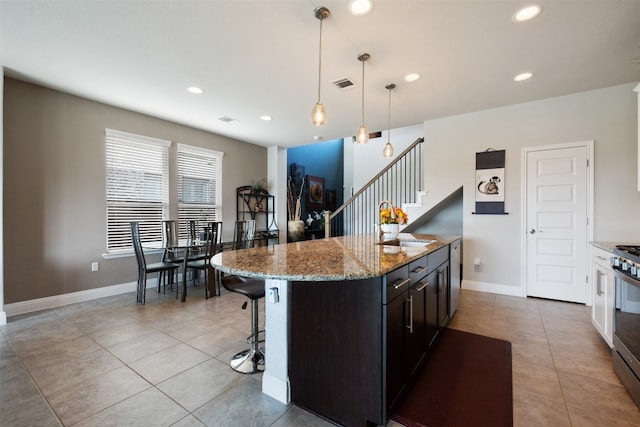 kitchen featuring a kitchen island, light tile patterned floors, pendant lighting, and light stone counters