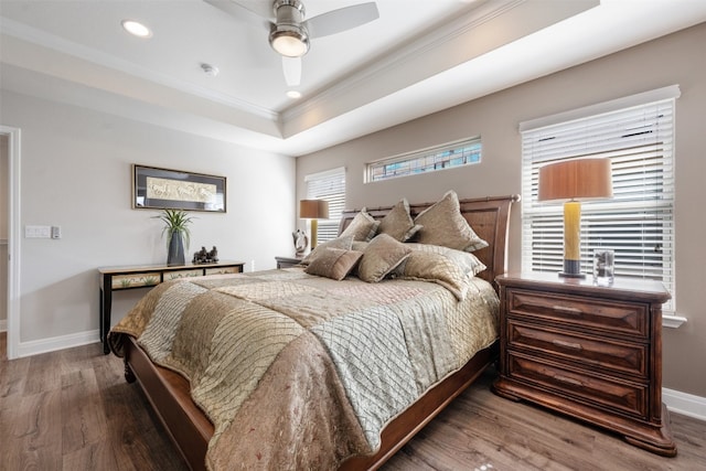 bedroom featuring wood-type flooring, ceiling fan, crown molding, and a tray ceiling