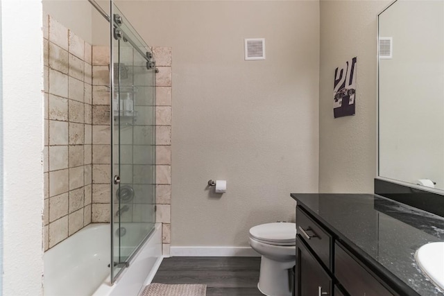 full bathroom featuring vanity, wood-type flooring, toilet, and combined bath / shower with glass door