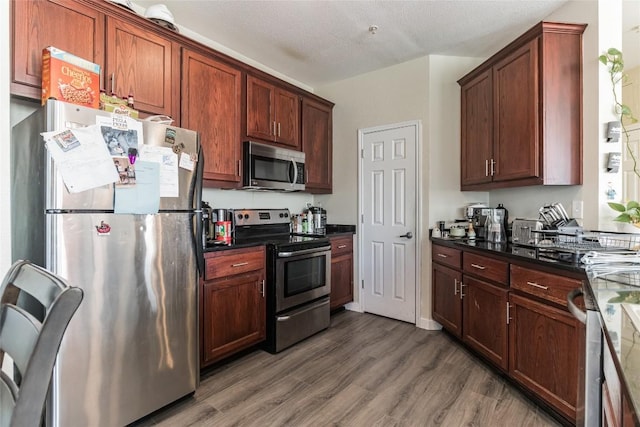 kitchen featuring dark hardwood / wood-style flooring, a textured ceiling, and appliances with stainless steel finishes