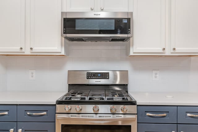 kitchen with white cabinetry, stainless steel appliances, backsplash, and blue cabinetry