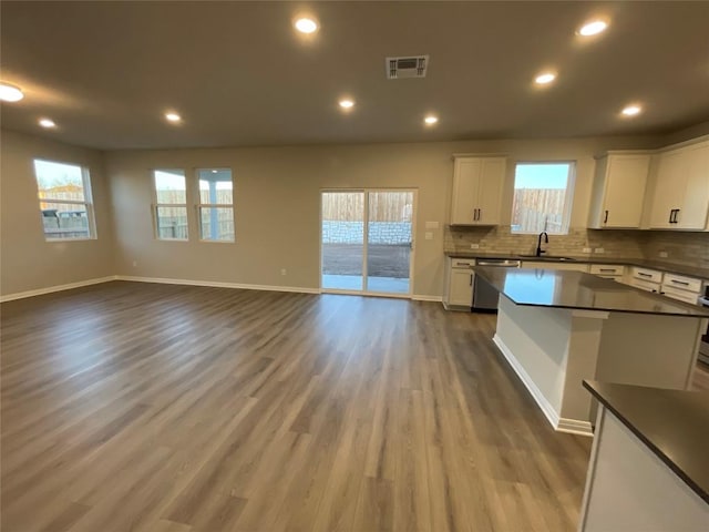 kitchen with dishwasher, sink, decorative backsplash, white cabinetry, and wood-type flooring