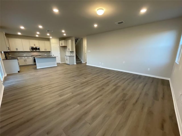 unfurnished living room with sink and dark wood-type flooring