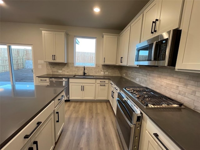 kitchen featuring decorative backsplash, sink, white cabinets, and appliances with stainless steel finishes