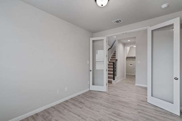 132 Scenic Hills Cir, Georgetown, TX 78628 - unfurnished room featuring baseboards, light wood-style flooring, stairs, and french doors