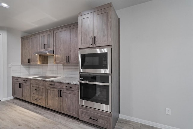 132 Scenic Hills Cir, Georgetown, TX 78628 - kitchen with oven, built in microwave, under cabinet range hood, black electric stovetop, and tasteful backsplash