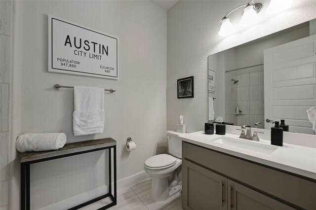 bathroom with toilet, vanity, and a tile shower