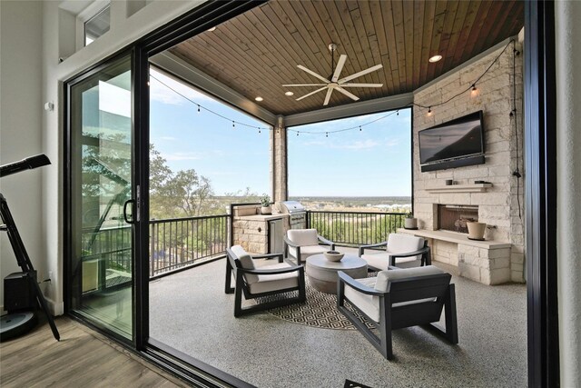 sunroom featuring ceiling fan, wood ceiling, and an outdoor stone fireplace