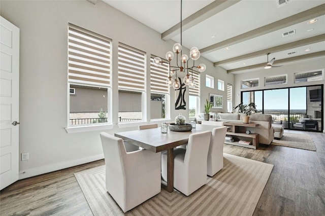 dining area with beamed ceiling, hardwood / wood-style floors, ceiling fan with notable chandelier, and plenty of natural light