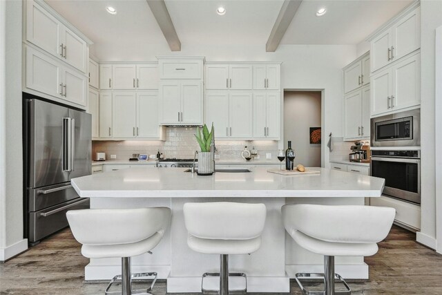 kitchen with a kitchen island with sink, appliances with stainless steel finishes, and dark hardwood / wood-style floors