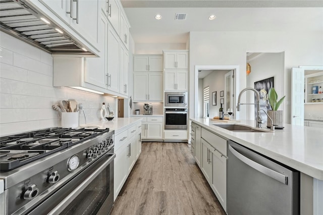 kitchen with stainless steel appliances, white cabinets, sink, and light wood-type flooring